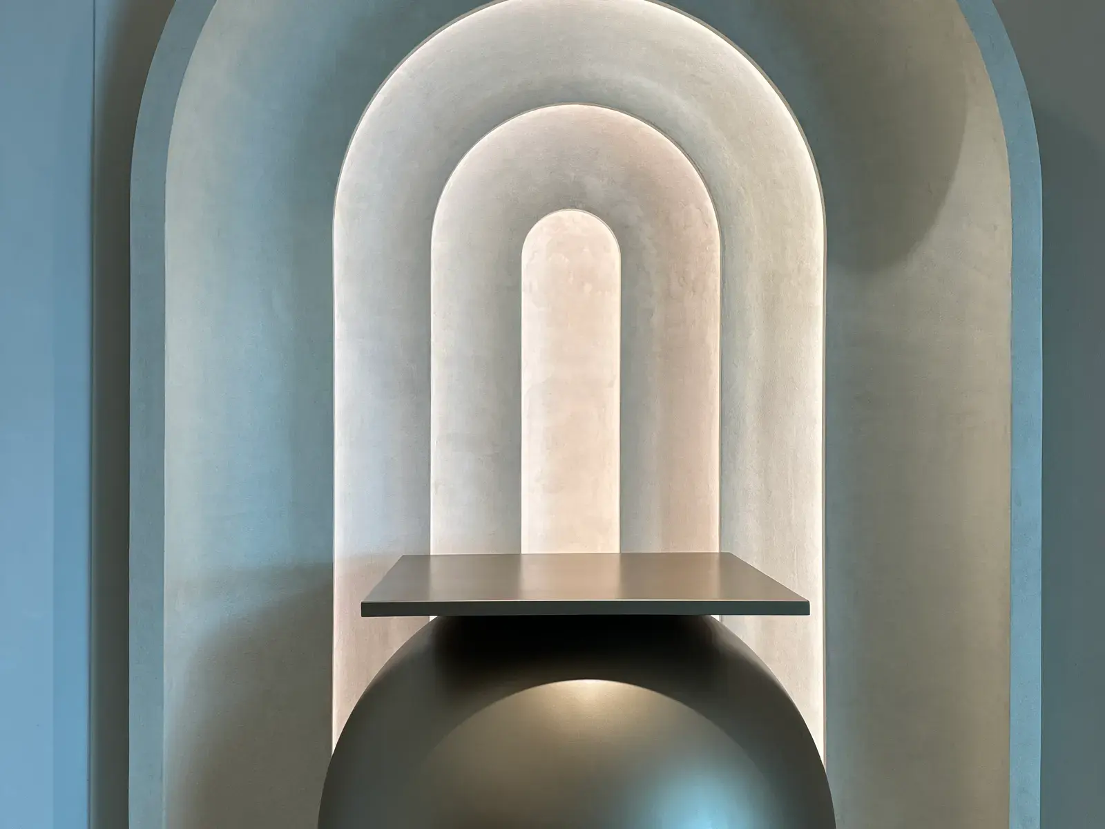 Arched niche carved into textured plaster with a floating console beneath