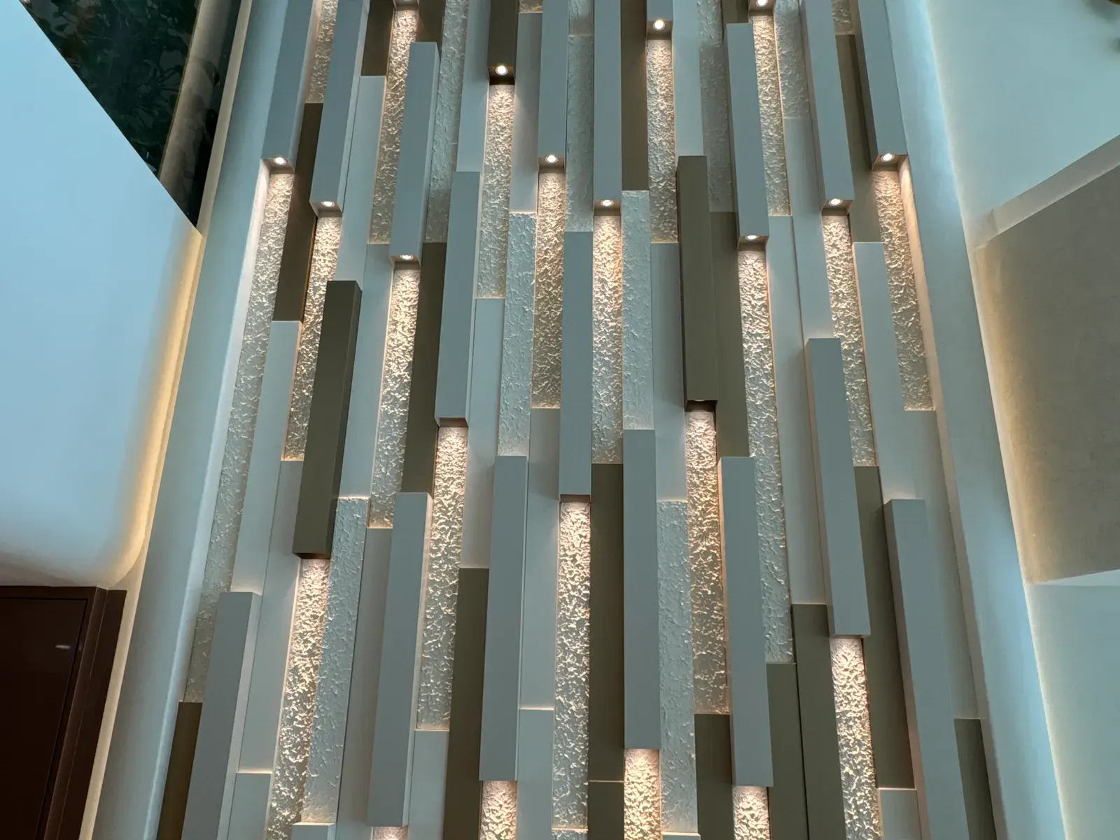 Screen of brass fins and fluted glass lit from within