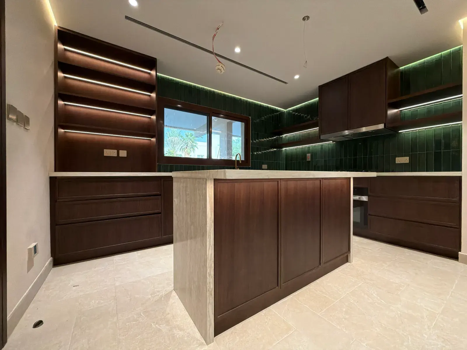 Walnut kitchen with island and green zellige splashback in a Jumeirah Islands villa