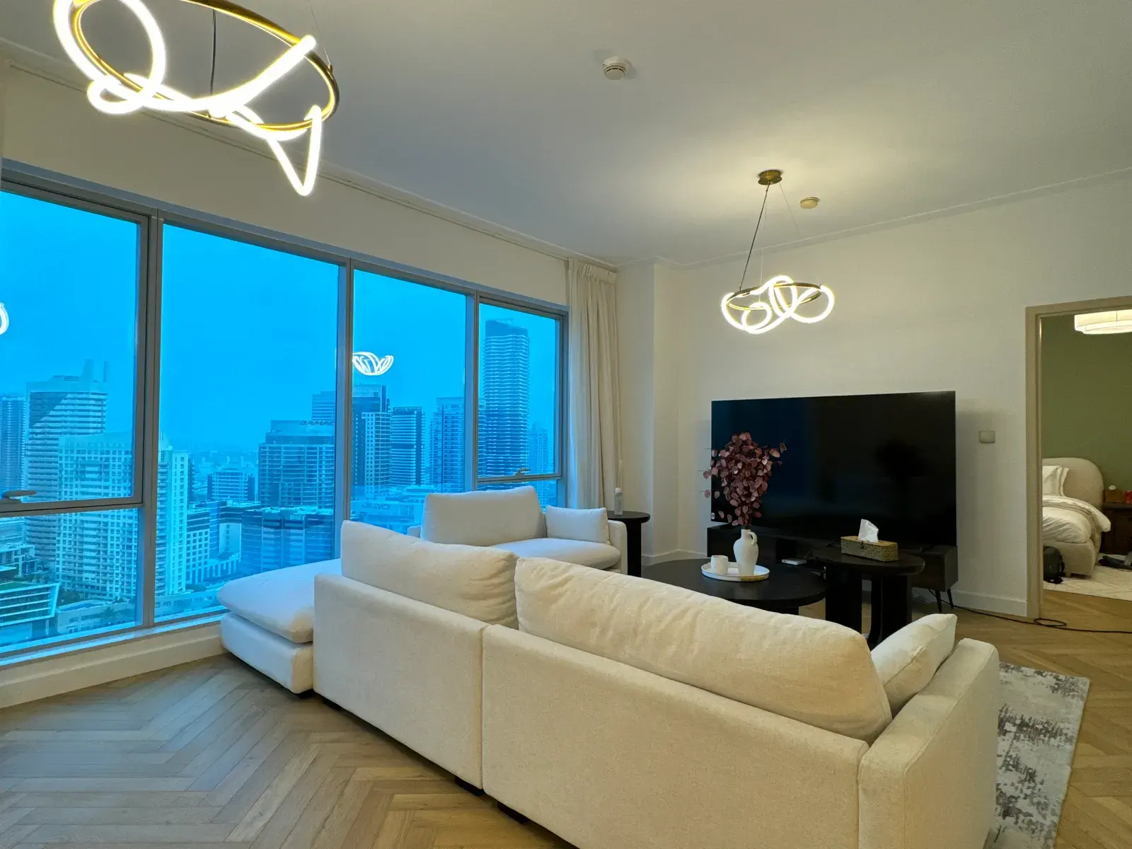 Living room with herringbone oak floor and full-height glazing over Dubai Marina