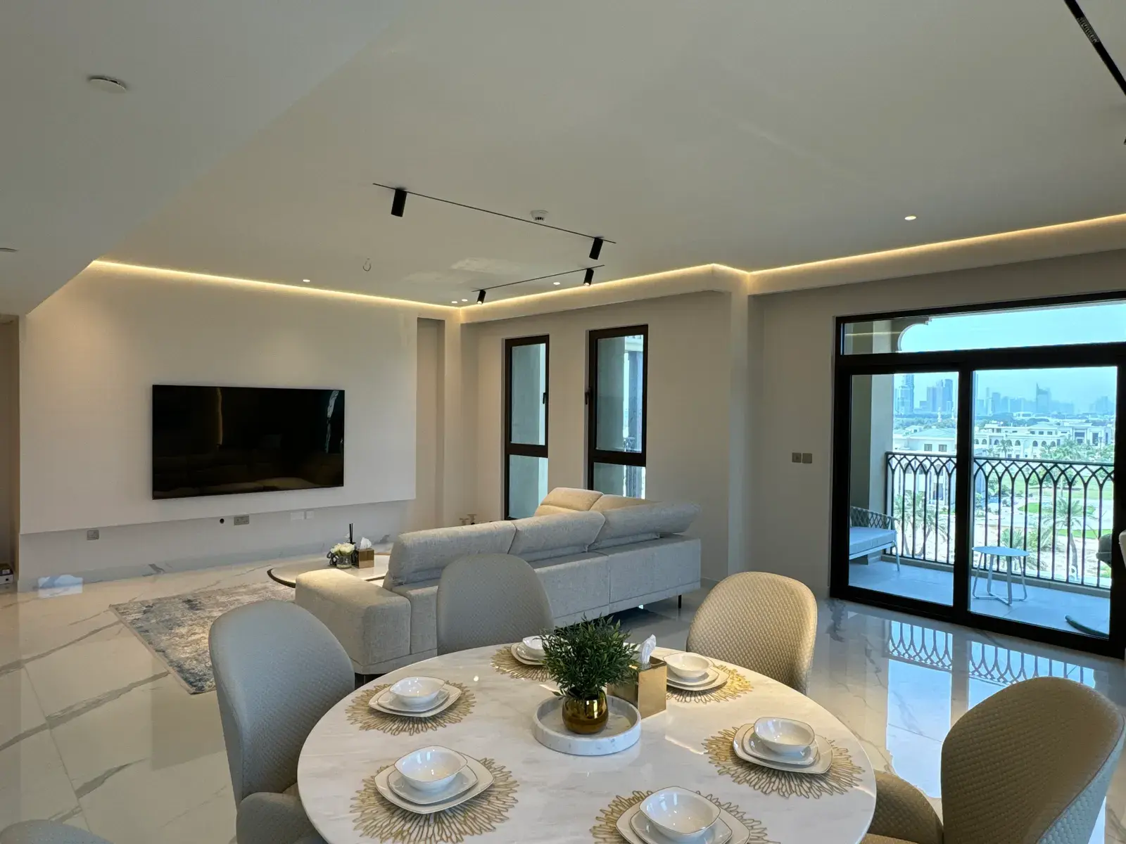 Open-plan living and dining room with cove lighting and a balcony beyond