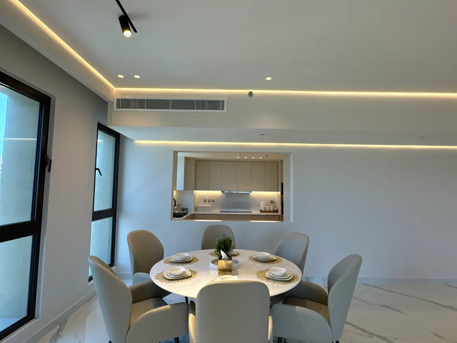 Round dining table beside a pass-through opening to the kitchen