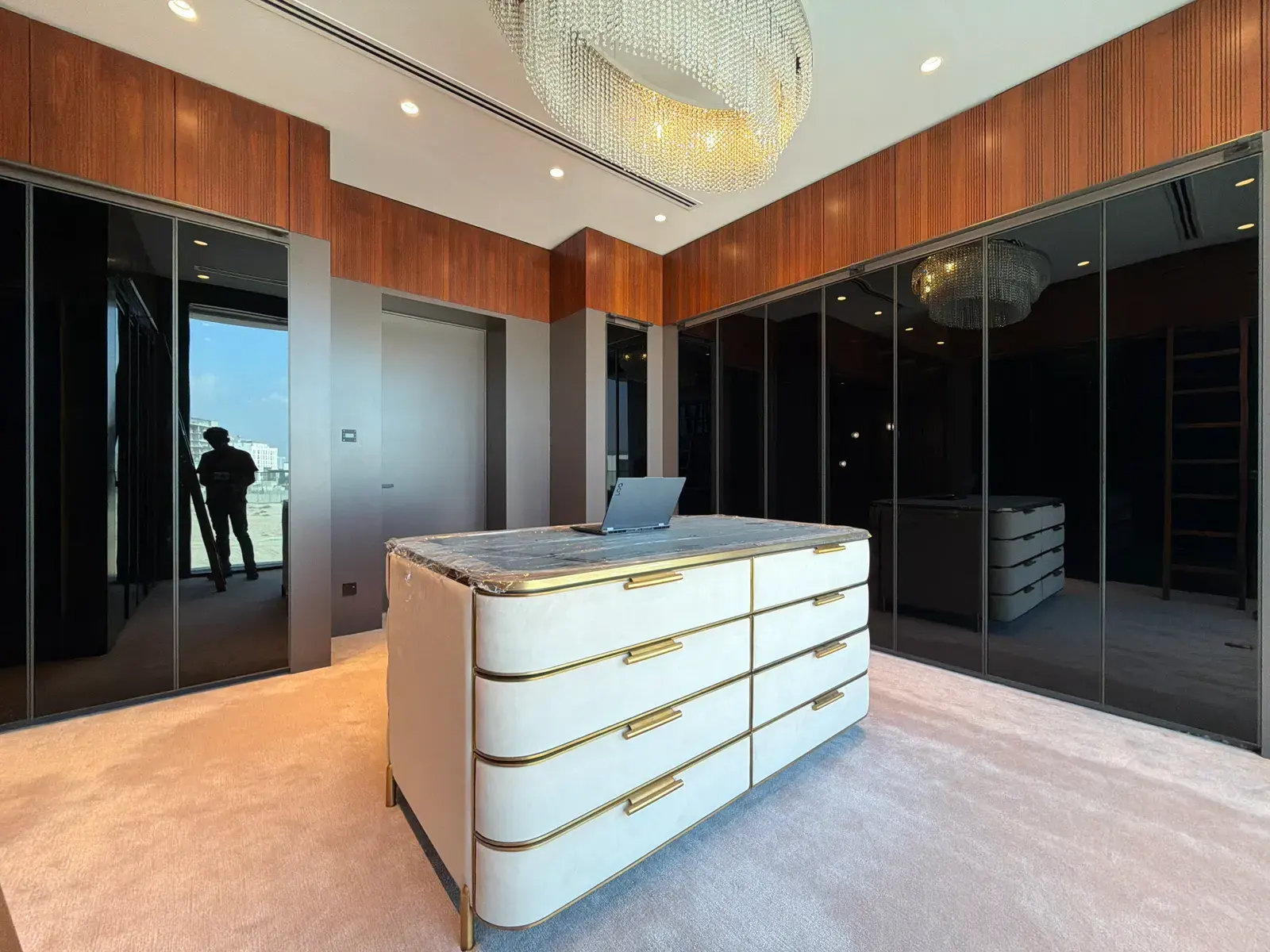 Dressing room with mirrored joinery and a brass-trimmed island