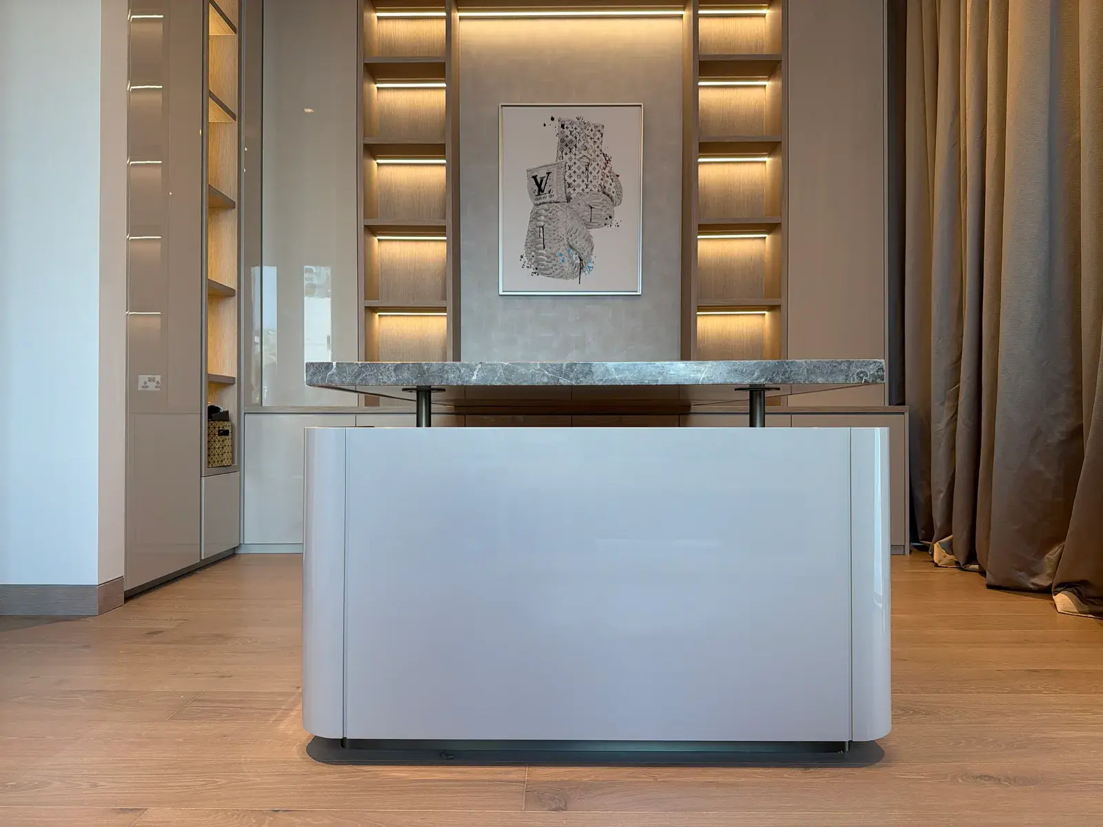 Kitchen island with a stone top in front of a backlit display wall