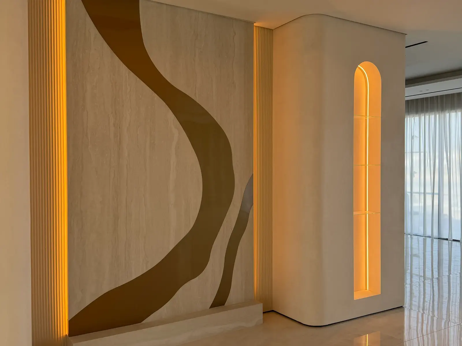 Travertine feature wall with a curved brass inlay and backlit arched niche