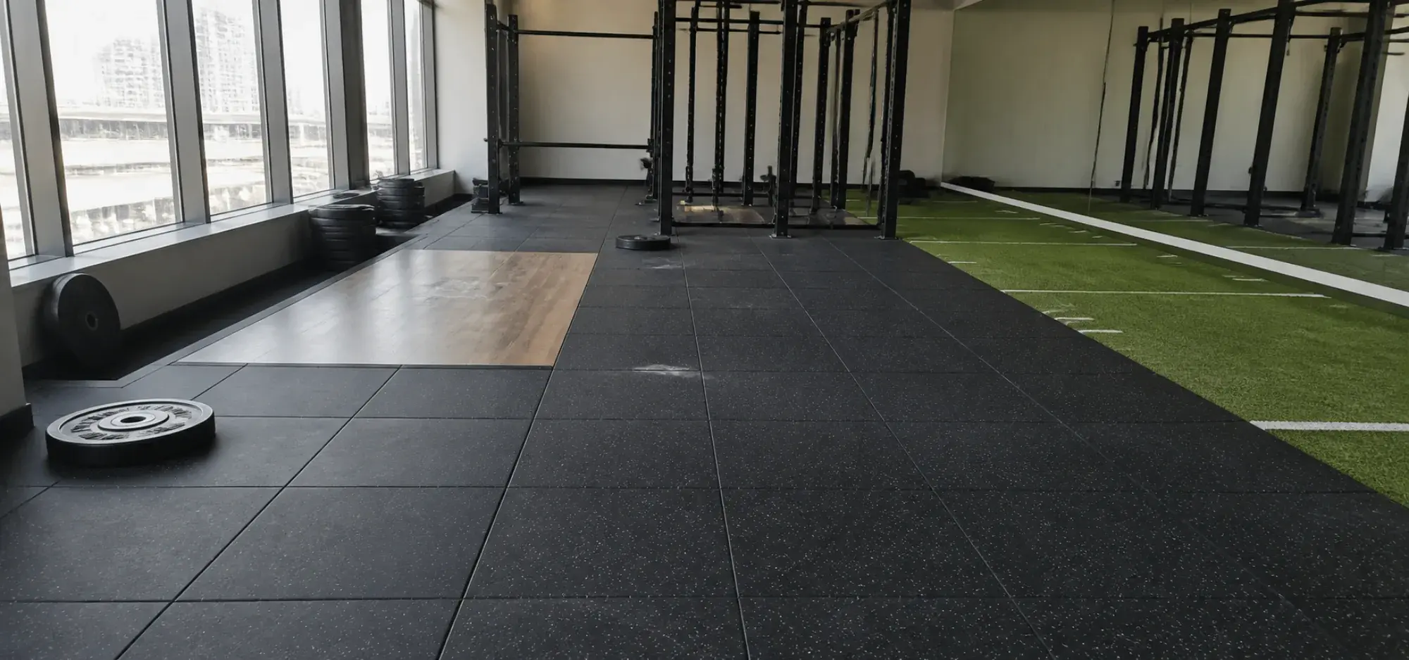 Heavy-duty rubber gym flooring laid in a Dubai fitness facility with a platform inlay and turf sprint track