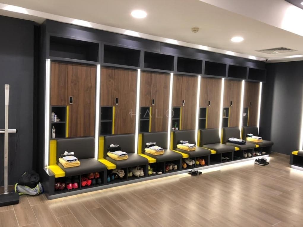 Gym locker room with bespoke timber locker banks, bench seating and integrated lighting