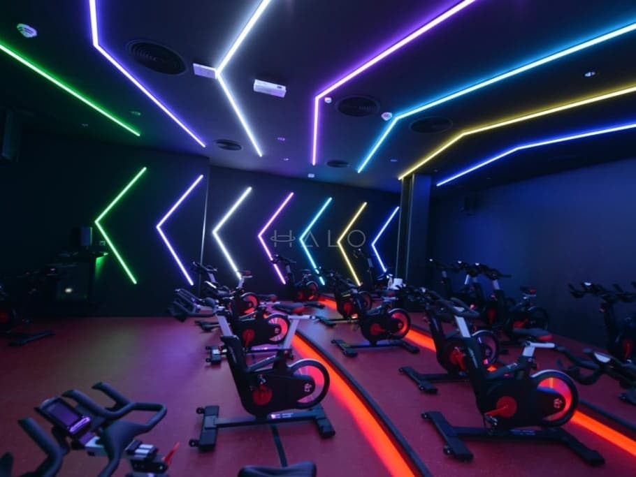 Indoor cycling studio with coloured LED ceiling and wall lighting and a poured resin floor