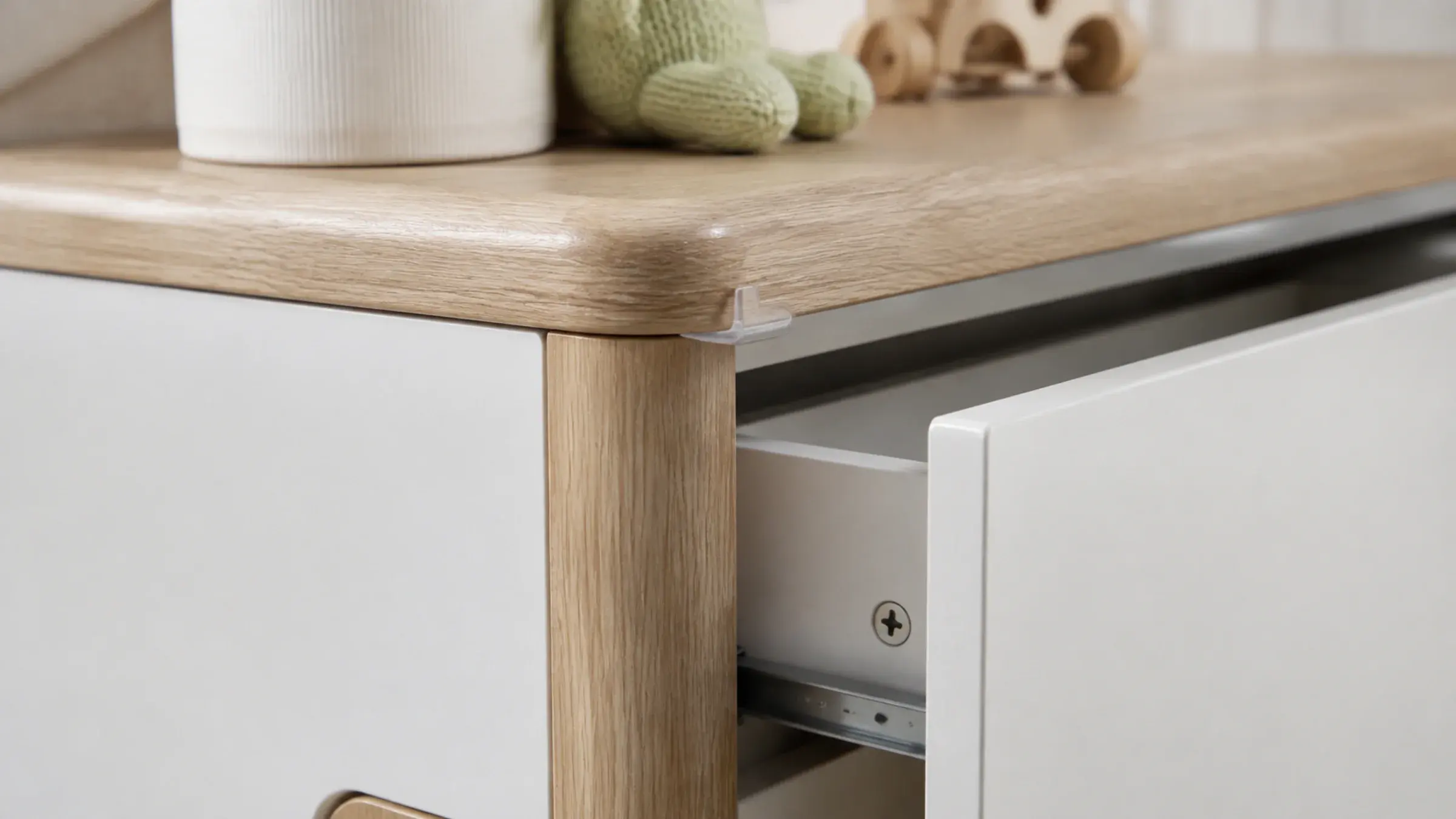 Close detail of a rounded furniture corner and a soft-close drawer mechanism on a kids' bedroom cabinet