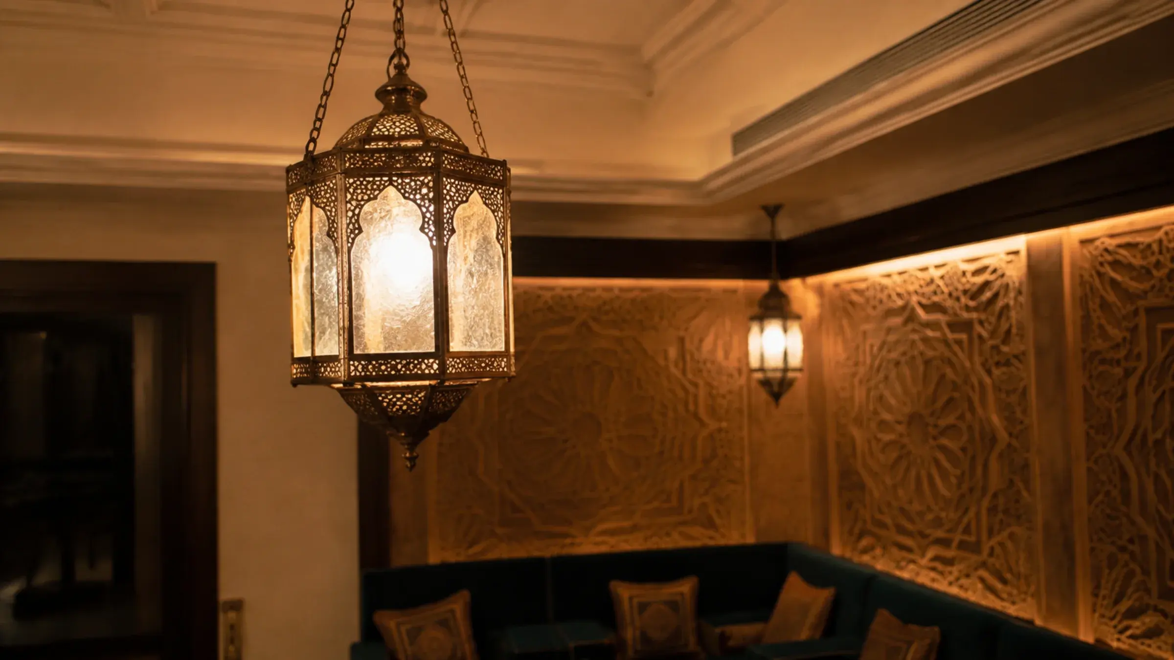 Pierced brass Moroccan-style lantern pendant lit above dark fluted wall panelling in a majlis