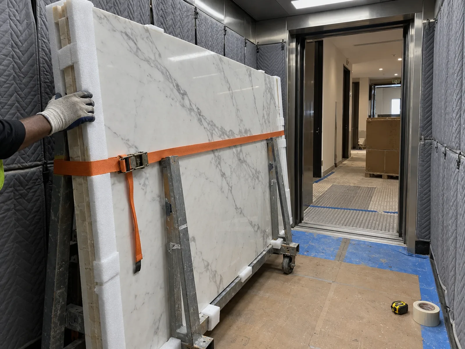 Marble slab on an A-frame trolley inside a padded tower service lift during a penthouse renovation