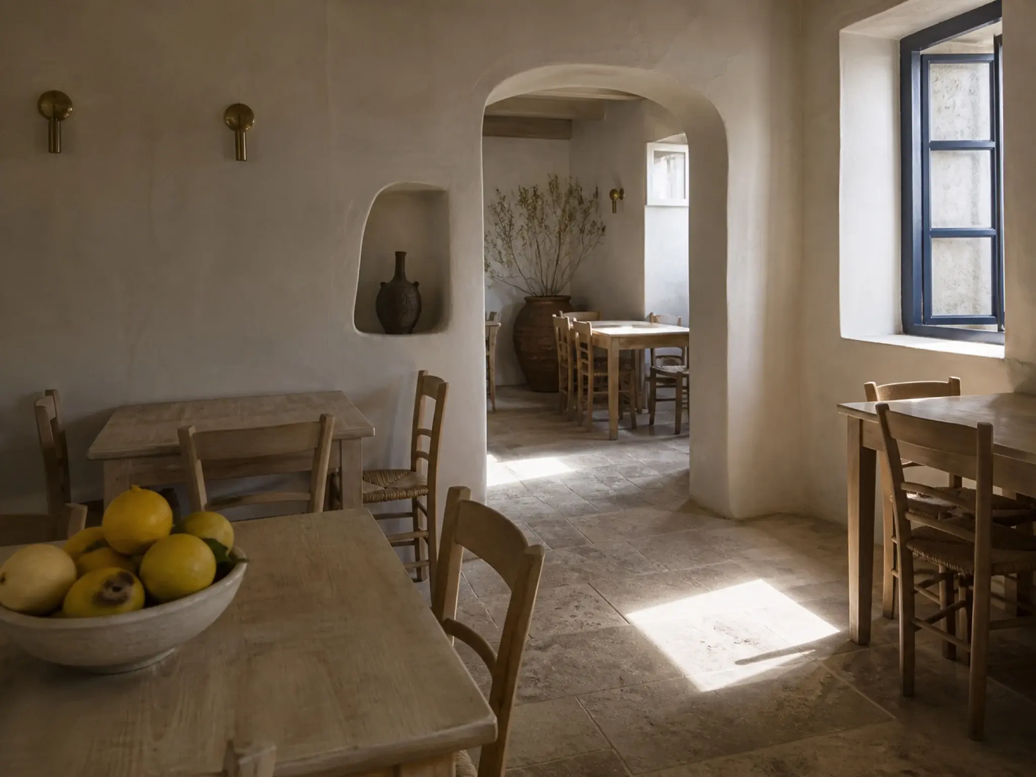 Mediterranean coastal restaurant with lime-washed walls, arched openings and bleached timber furniture
