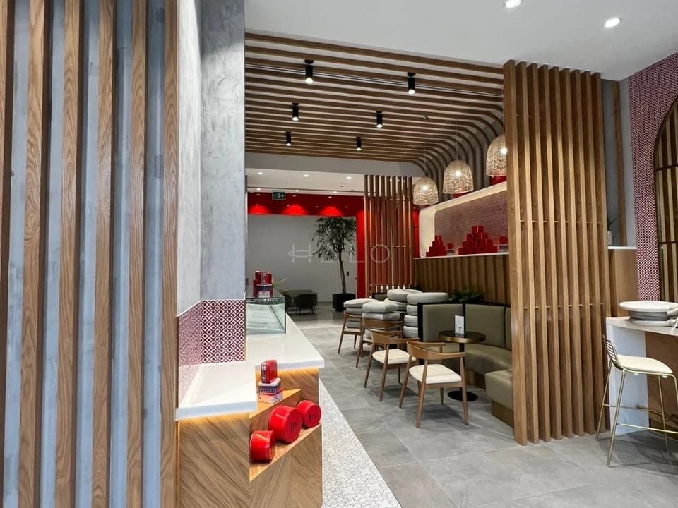 Salon interior design in Dubai with timber-fin partitions, banquette waiting seating and a red feature wall