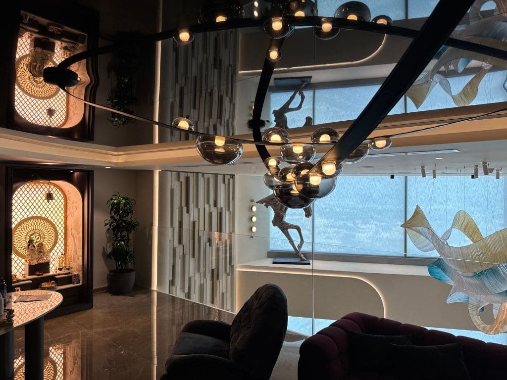 High-gloss dark stretch ceiling reflecting a chandelier and mashrabiya screening in a Dubai majlis