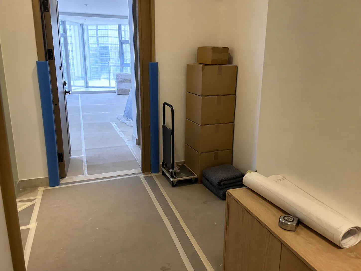 Apartment entrance with door-frame padding, taped floor protection and materials staged for a booked service lift slot
