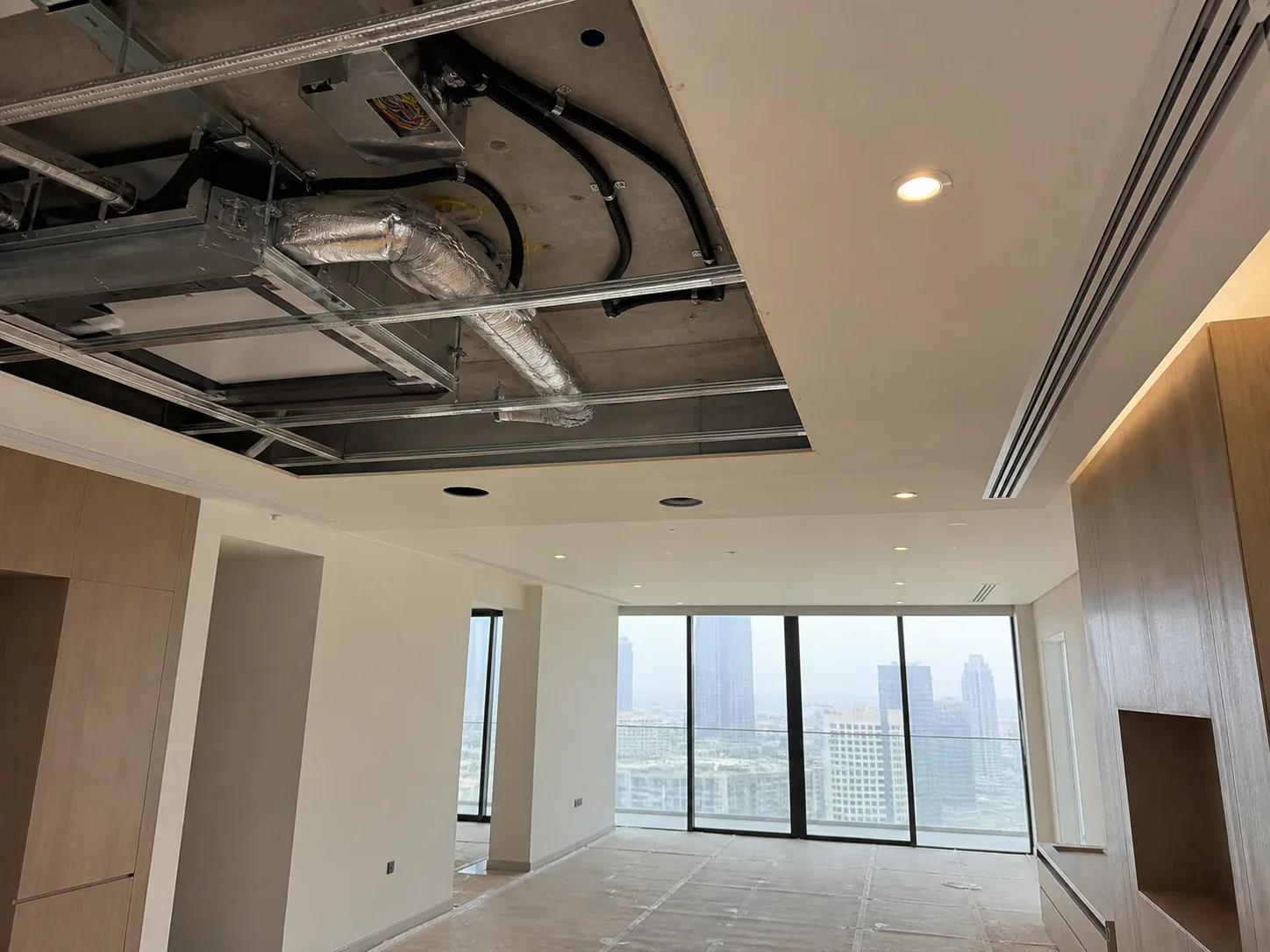 Open ceiling in a Dubai apartment showing the fan coil unit, insulated ductwork and cabling within a shallow ceiling void